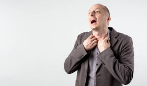 Mann hält sich beide Hände an den Hals und ringt um Luft