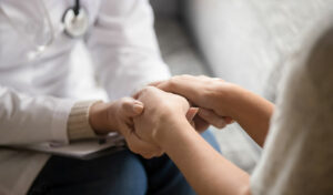 Ein Arzt hält während einer Konsultation die Hände eines Patienten und bietet ihm Trost und Unterstützung.