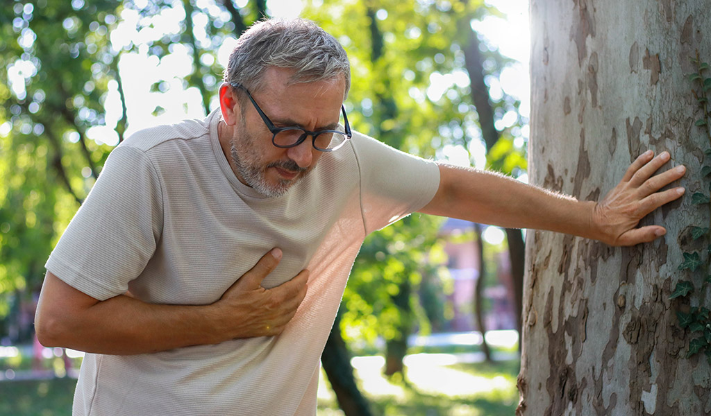 Mann hat Atemnot und hält sich die Hand vor die Brust