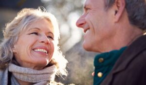 Lächelndes älteres Paar im Freien, warm gekleidet, schaut sich glücklich an.