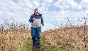 Älterer Herr im Sportoutfit joggt auf Grünland