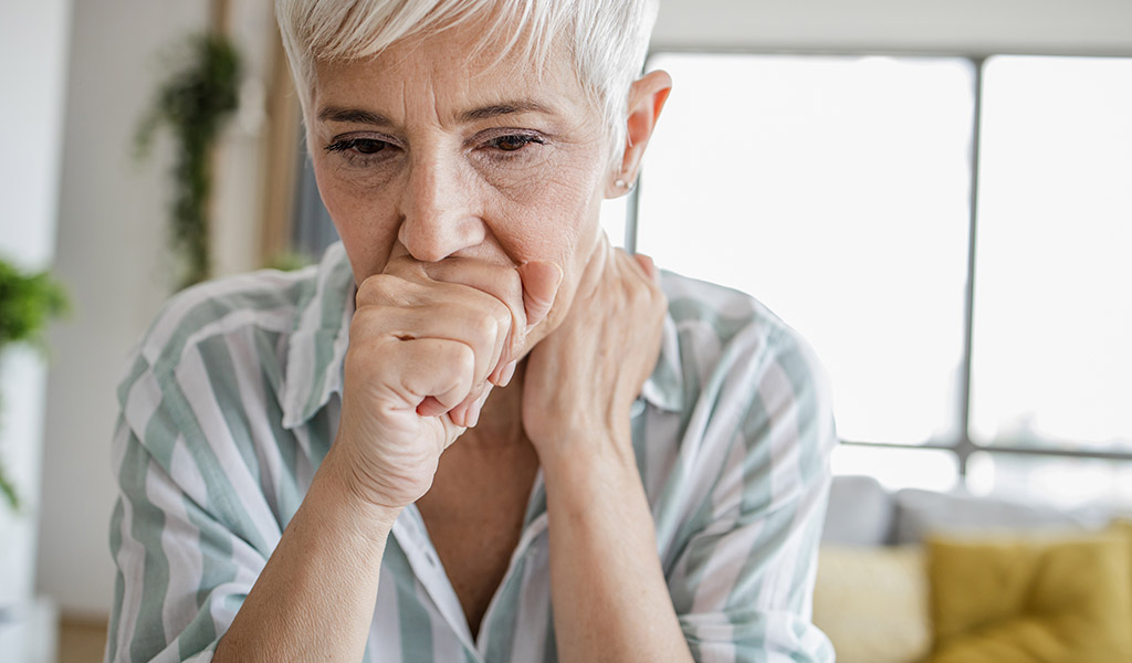 Frau hält sich die Hand vor den Mund beim Husten