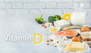 Vitamin-D-reiche Lebensmittel, darunter Fisch, Eier, Käse, Milch, Nüsse, Pilze, Brokkoli und Orangen auf einem Tisch.